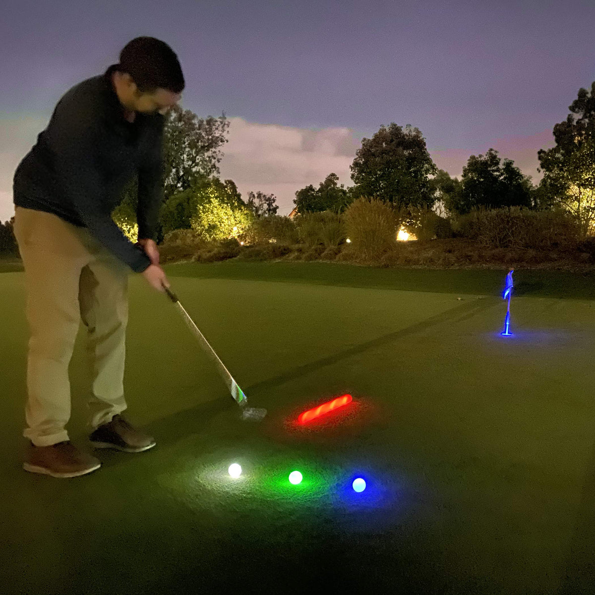 GoSports night golf practice scene showing illuminated balls after dark.
